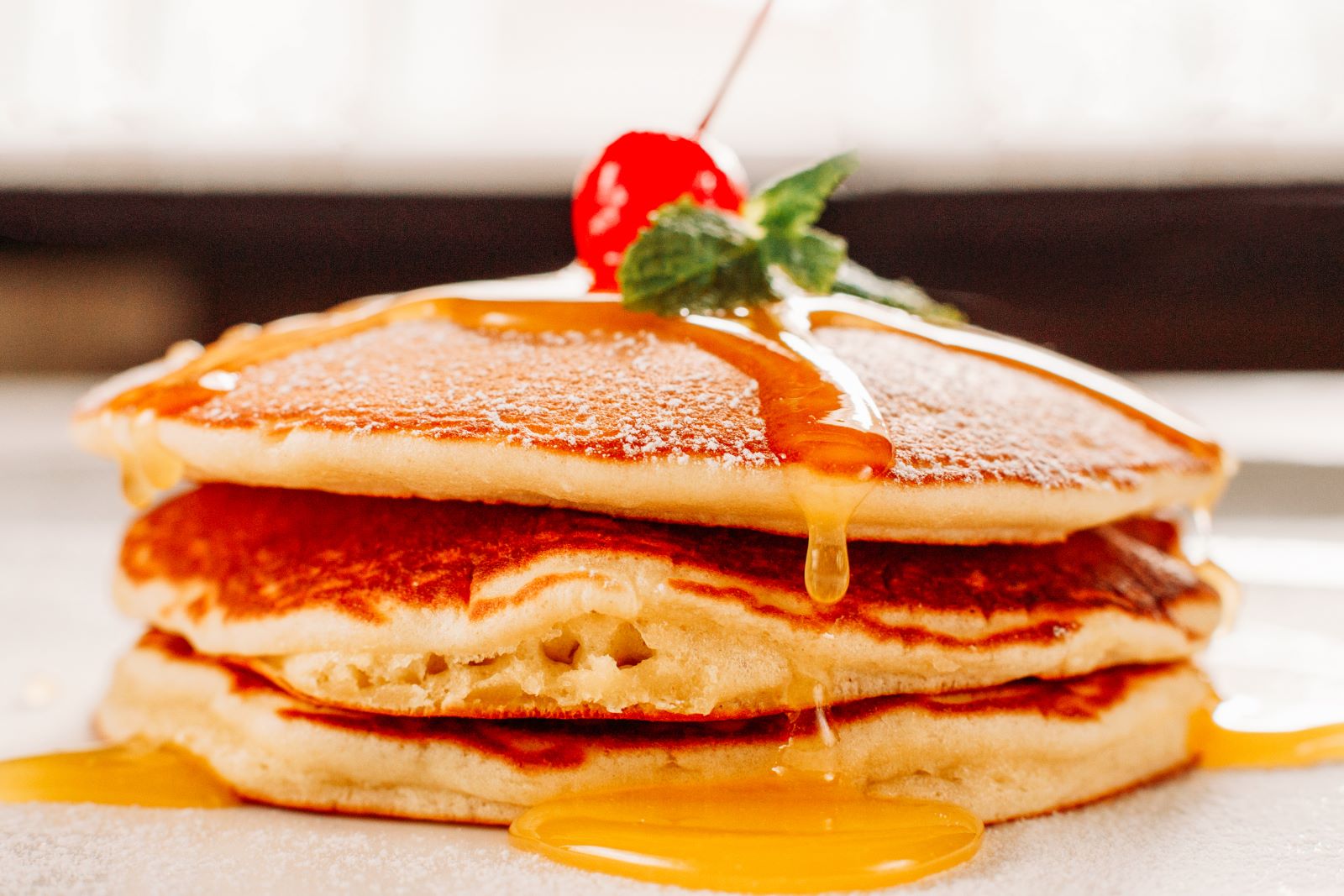 A stack of pancakes with a cherry on top.