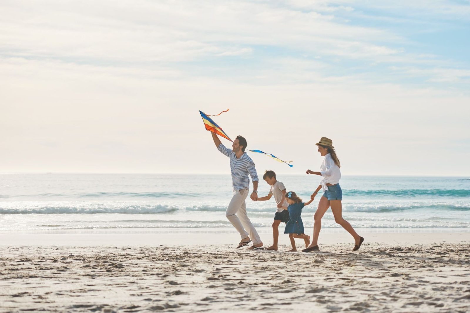 Family, holding hands and kite on beach